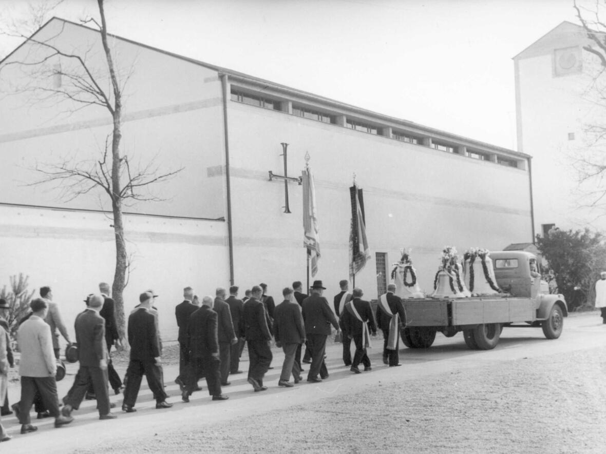 Die neuen Glocken treffen ein und werden von zahlreichen Gläubigen bis vor die Kirche geleitet.