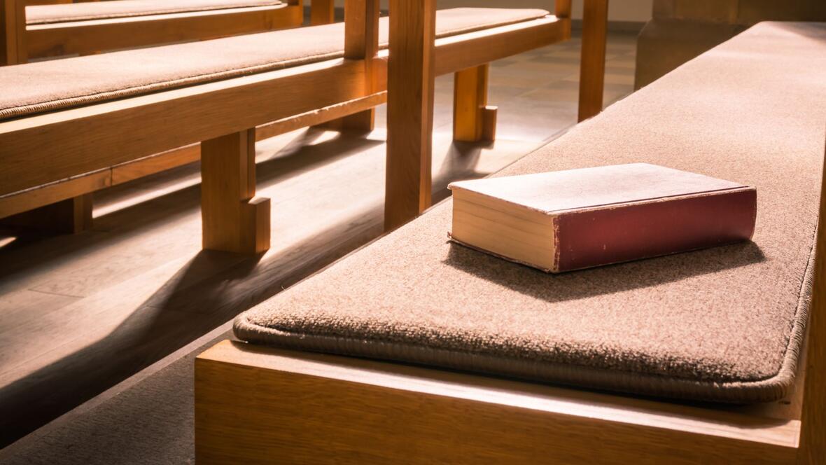 Eine Bibel liegt auf einer Kirchenbank
